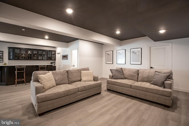 living room with wet bar, recessed lighting, baseboards, and light wood finished floors