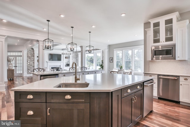 kitchen featuring a kitchen island with sink, white cabinets, stainless steel appliances, and a sink