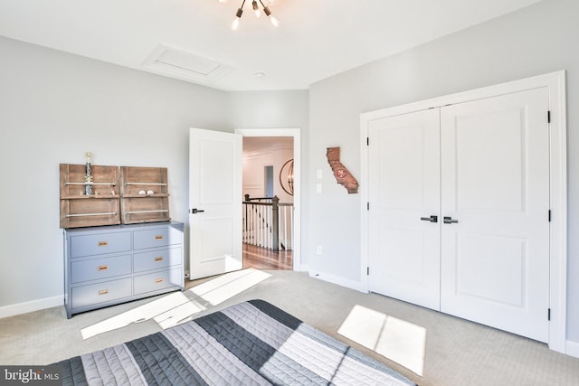 unfurnished bedroom with a closet, baseboards, light colored carpet, and attic access