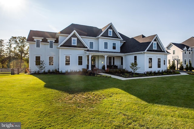 view of front facade featuring covered porch, a front yard, and fence