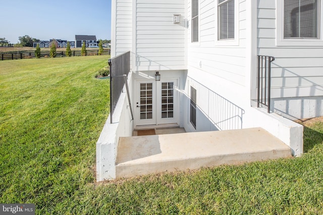 property entrance featuring a lawn and fence