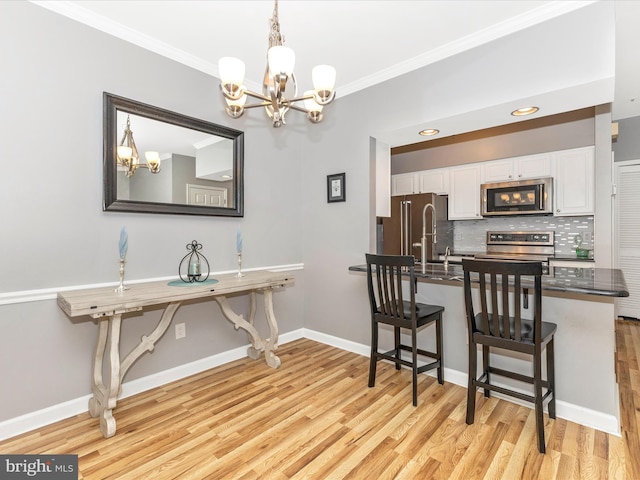 dining area featuring baseboards, light wood-type flooring, ornamental molding, recessed lighting, and an inviting chandelier