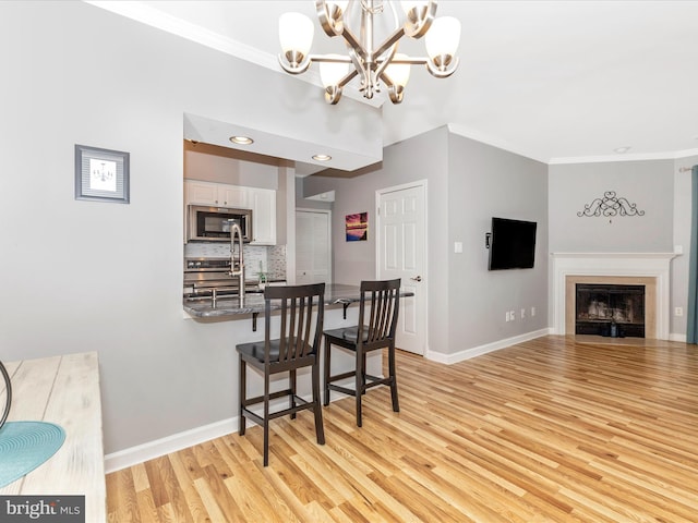 dining area featuring light wood finished floors, baseboards, an inviting chandelier, and ornamental molding