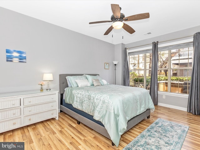 bedroom with visible vents, a ceiling fan, baseboards, and wood finished floors