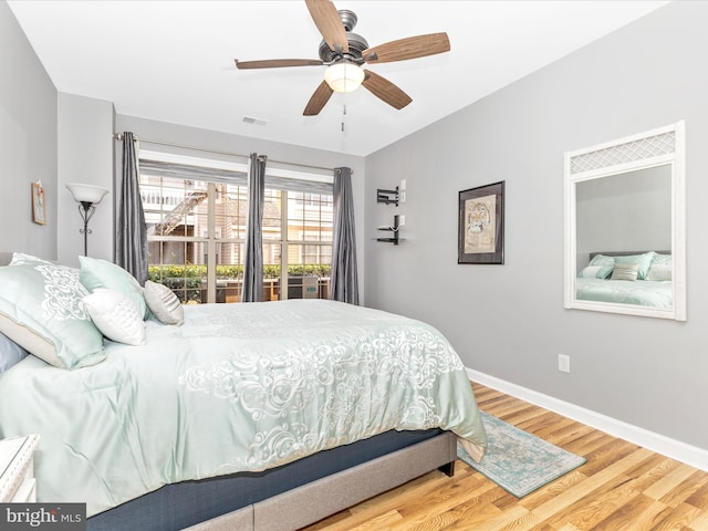 bedroom with ceiling fan, wood finished floors, visible vents, and baseboards