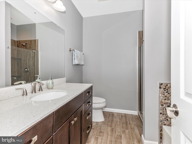 full bathroom with a shower with shower door, toilet, wood finished floors, baseboards, and vanity