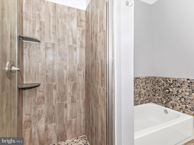 bathroom with a stall shower and a garden tub