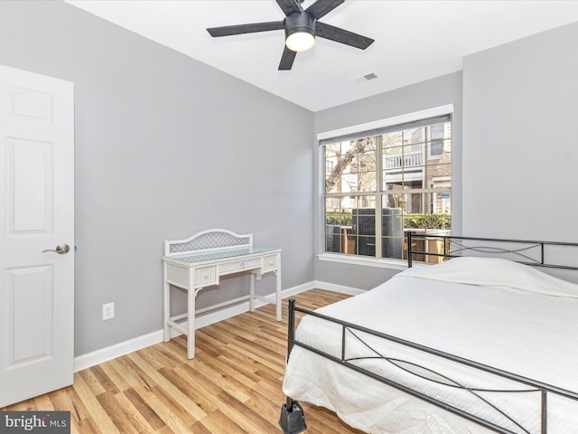 bedroom with visible vents, a ceiling fan, baseboards, and wood finished floors