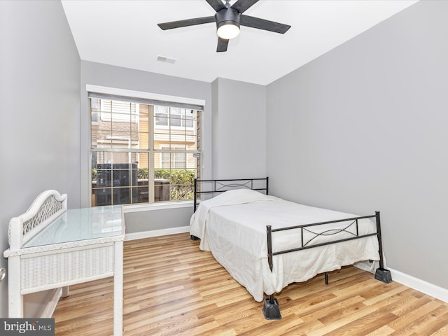 bedroom featuring ceiling fan, visible vents, baseboards, and wood finished floors