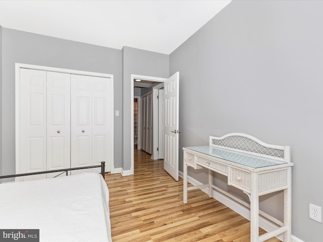 bedroom featuring a closet, light wood-style flooring, and baseboards