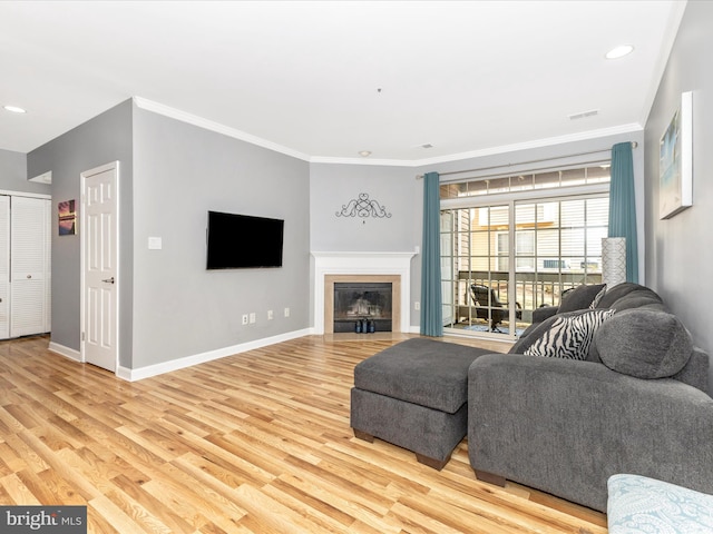 living area with light wood finished floors, baseboards, and ornamental molding