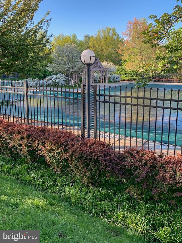 view of swimming pool with a water view and fence