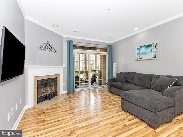 living room featuring wood finished floors, visible vents, baseboards, a fireplace with flush hearth, and crown molding