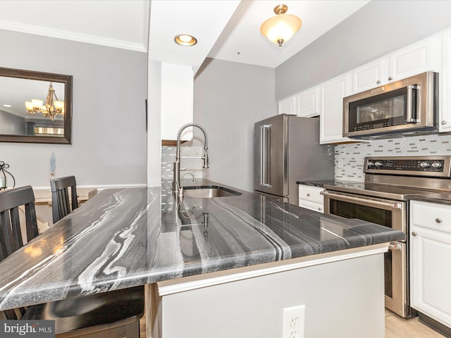 kitchen with a sink, stainless steel appliances, tasteful backsplash, and white cabinetry