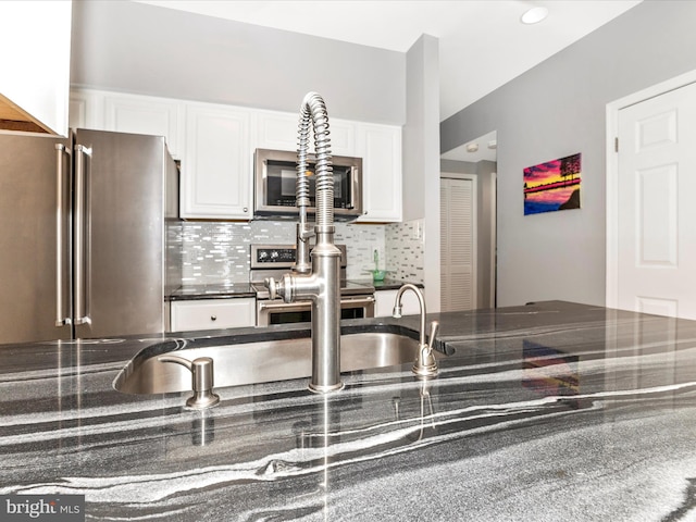 kitchen featuring dark stone counters, tasteful backsplash, appliances with stainless steel finishes, and white cabinetry