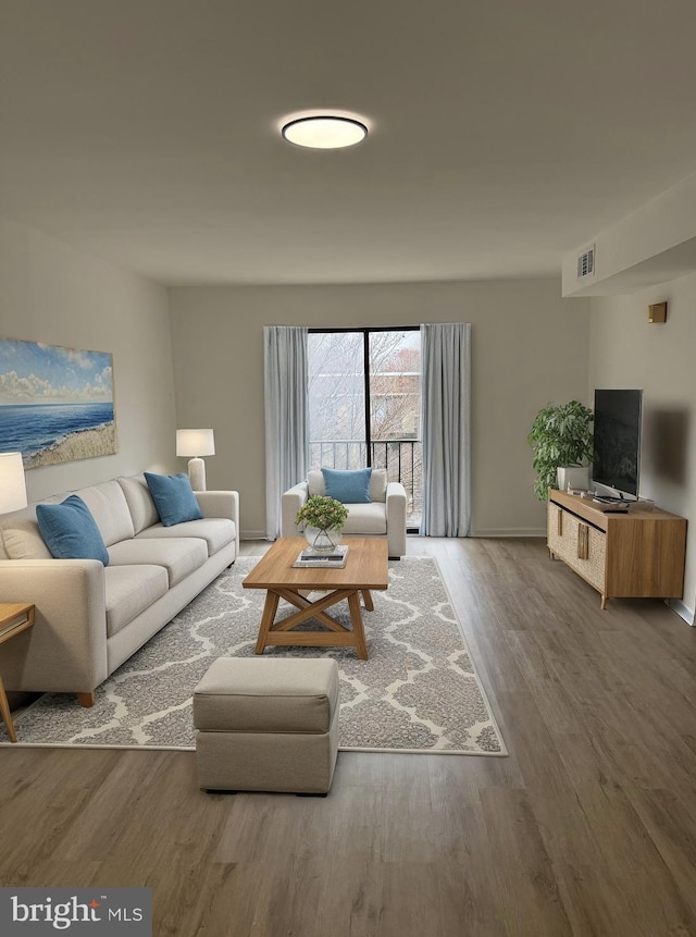 living area with visible vents, baseboards, and wood finished floors