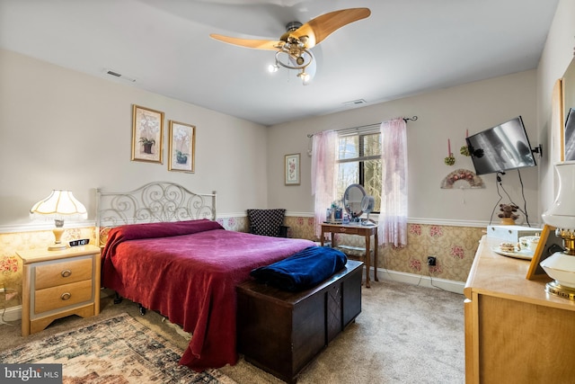 bedroom with a wainscoted wall, light carpet, visible vents, and wallpapered walls