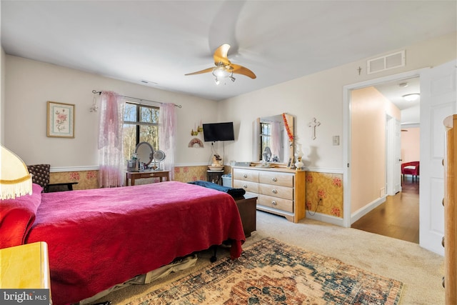 carpeted bedroom featuring a ceiling fan, visible vents, and baseboards