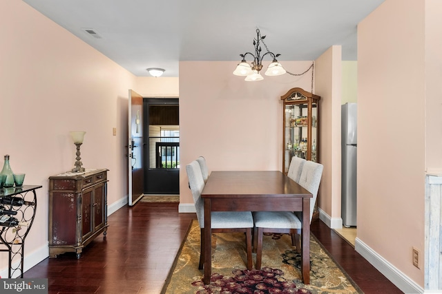 dining space featuring visible vents, baseboards, a notable chandelier, and dark wood-style floors