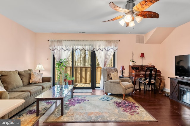 living area featuring baseboards, wood finished floors, visible vents, and ceiling fan