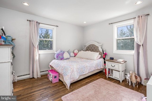 bedroom with baseboard heating, multiple windows, and wood-type flooring