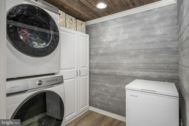 washroom with wood finished floors, cabinet space, stacked washer and dryer, wood ceiling, and wood walls