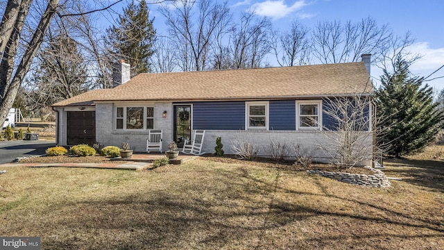 ranch-style house with a front lawn, roof with shingles, a garage, brick siding, and a chimney