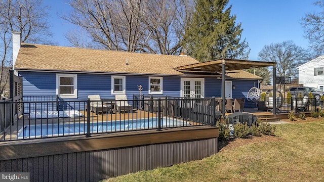 back of property featuring a deck, a chimney, and a shingled roof