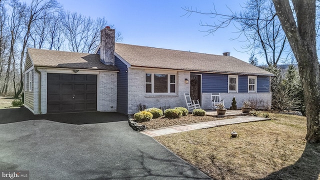 ranch-style home with brick siding, a shingled roof, a chimney, a garage, and driveway