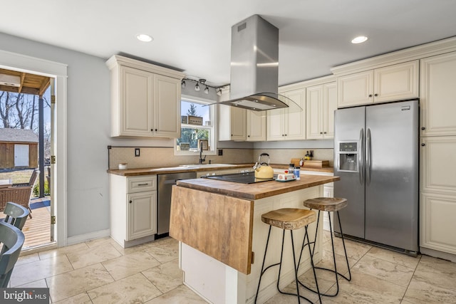 kitchen featuring butcher block countertops, cream cabinetry, stainless steel appliances, and island range hood