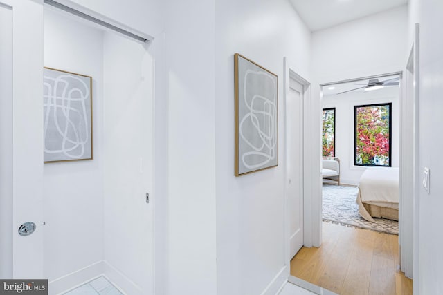 hallway featuring light wood-style flooring and baseboards