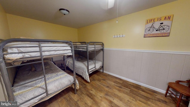 bedroom featuring wood finished floors, baseboards, and wainscoting