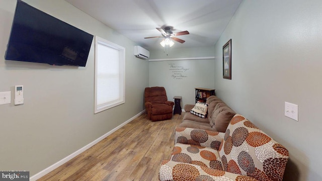 sitting room featuring baseboards, a wall mounted AC, a ceiling fan, and wood finished floors