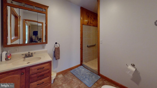 full bath with vanity, baseboards, and tiled shower