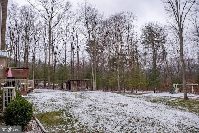 yard covered in snow featuring playground community and a deck