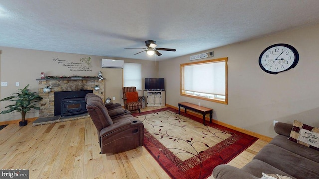 living room with ceiling fan, a wall mounted air conditioner, baseboards, and hardwood / wood-style flooring