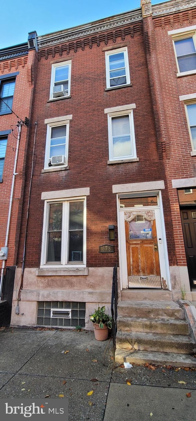 townhome / multi-family property with cooling unit and brick siding