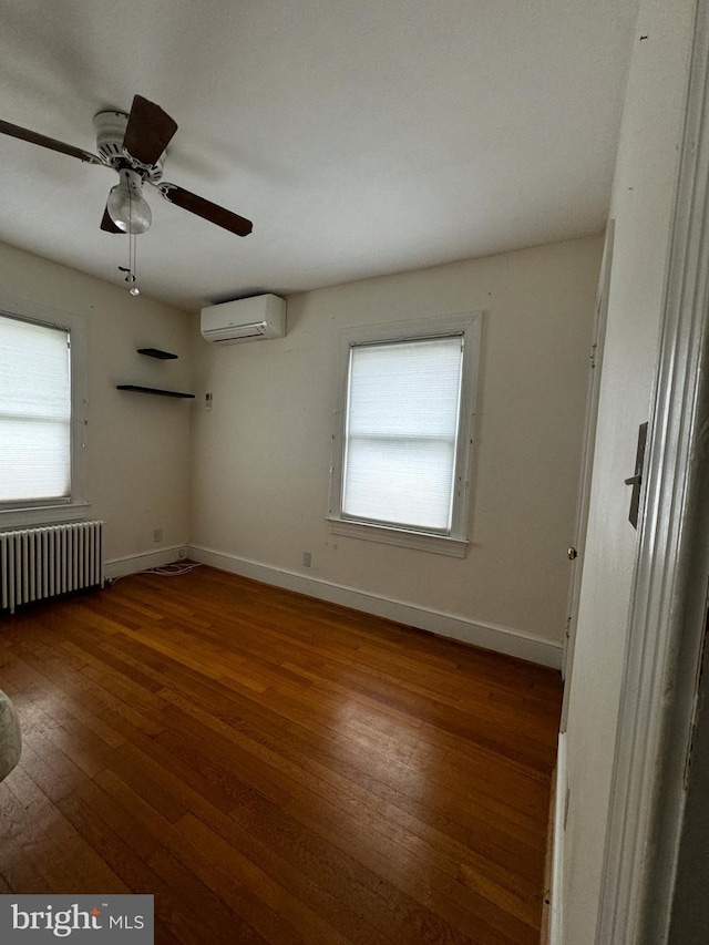 empty room with baseboards, wood-type flooring, radiator, and an AC wall unit