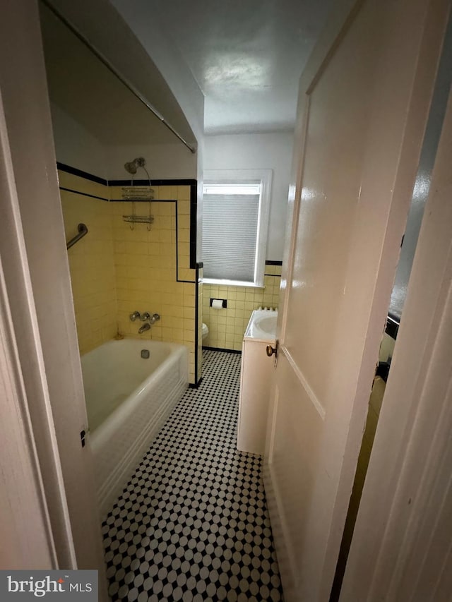 full bath featuring vanity, tile walls, toilet, and shower / washtub combination