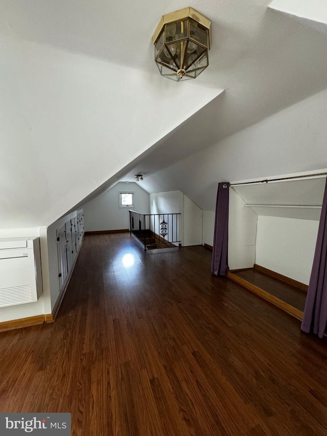 additional living space featuring vaulted ceiling, baseboards, and wood finished floors