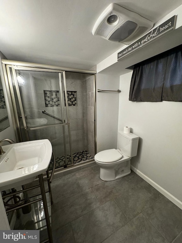 full bathroom with a shower stall, toilet, baseboards, and a sink