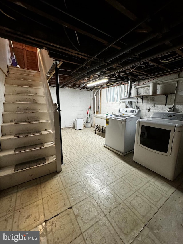 below grade area with washer and clothes dryer, light floors, and stairs