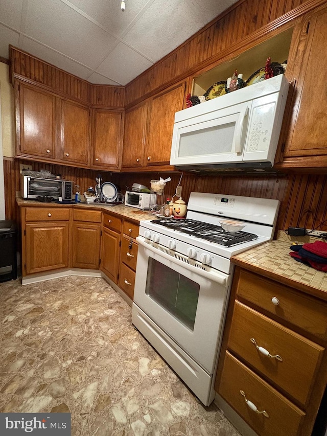 kitchen featuring brown cabinetry, a toaster, and white appliances