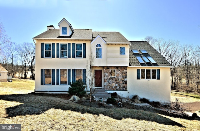 view of front of home with stone siding, solar panels, a chimney, and stucco siding