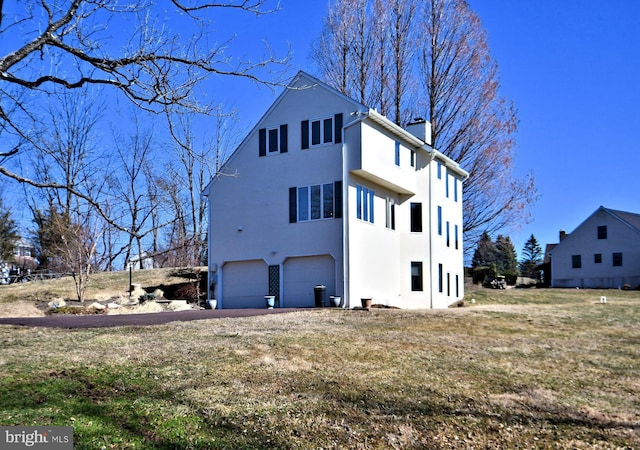 exterior space with driveway, a yard, stucco siding, a chimney, and a garage