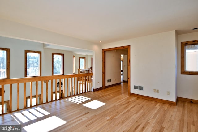 unfurnished room with visible vents, light wood-type flooring, and baseboards