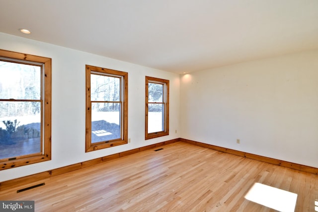 empty room featuring visible vents, baseboards, and light wood-style floors