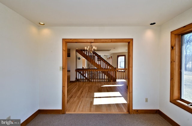 stairway with baseboards, plenty of natural light, and a notable chandelier