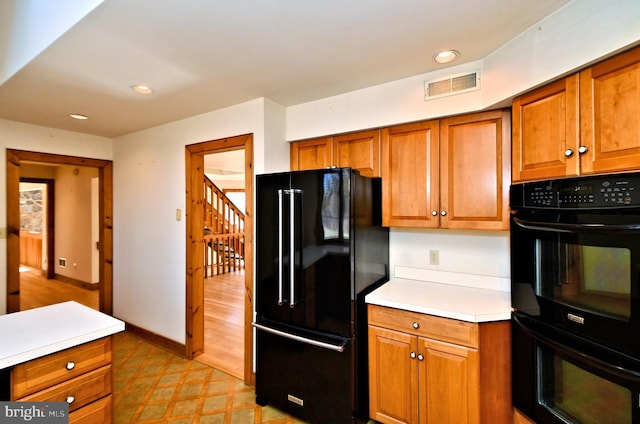 kitchen featuring visible vents, black appliances, and brown cabinetry