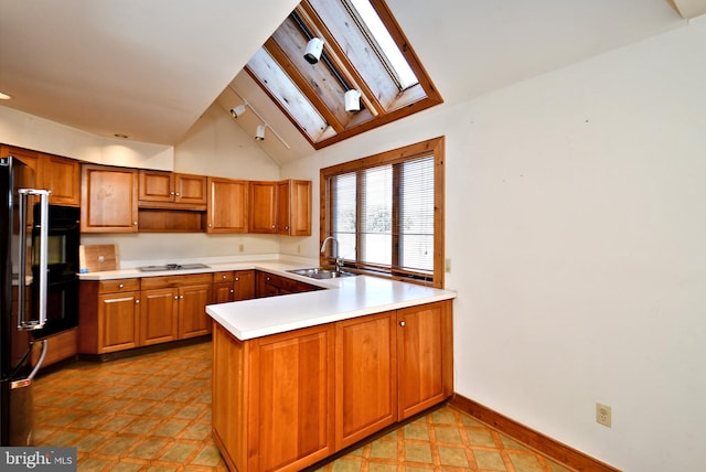 kitchen with a peninsula, stovetop, brown cabinets, and a sink